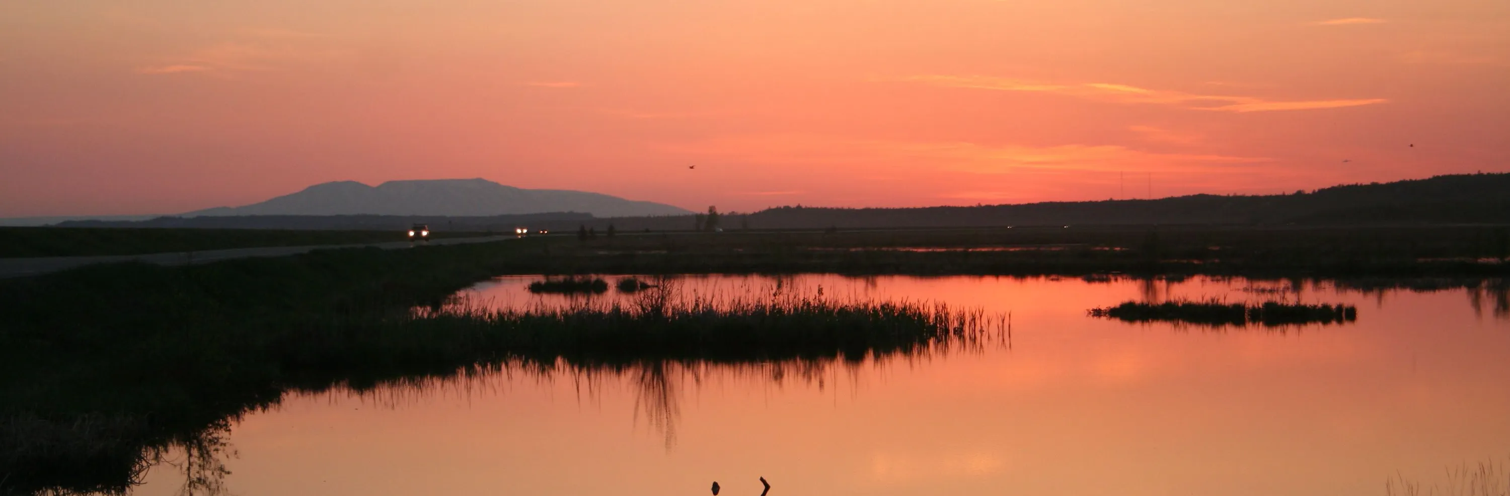 Sunset reflected in Potter Marsh beneath distant mountains